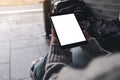 Woman`s hands holding and using black tablet pc with blank white desktop screen while sitting on the floor with baggages