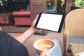 woman's hands holding black tablet pc with blank white screen while drinking coffee in cafe Royalty Free Stock Photo