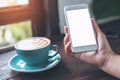 Mockup image of woman`s hands holding white mobile phone with blank screen and blue coffee cup Royalty Free Stock Photo