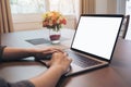 Woman`s hands using and typing on laptop with blank white desktop screen on wooden table in the house Royalty Free Stock Photo