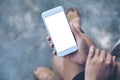 Mockup image of a woman sitting crossed leg and holding white mobile phone with blank desktop screen with concrete floor Royalty Free Stock Photo