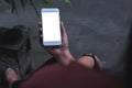 Mockup image of a woman sitting crossed leg and holding white mobile phone with blank screen with concrete floor Royalty Free Stock Photo