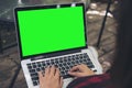 Mockup image of a woman sitting , using and typing on laptop with blank green screen on thigh at outdoor Royalty Free Stock Photo