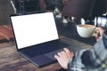 A woman using laptop with blank white desktop screen while drinking hot coffee in cafe Royalty Free Stock Photo