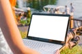A mockup image of a woman using a laptop with a blank white desktop screen, sitting by the sea against a background of blue water. Royalty Free Stock Photo