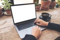 Woman using and typing on laptop with blank white desktop screen on vintage wooden table in cafe Royalty Free Stock Photo