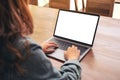 A woman using and typing on laptop with blank white desktop screen on wooden table in office Royalty Free Stock Photo