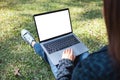 A woman using and typing on laptop with blank white screen , sitting in the outdoors Royalty Free Stock Photo