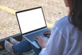 A woman using and typing on laptop with blank white screen , sitting in the parking lot outdoors Royalty Free Stock Photo