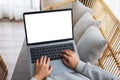 A woman working and typing on laptop computer with blank screen while sitting on a sofa at home Royalty Free Stock Photo