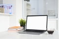 Mockup image of workspace with blank screen laptop and coffee cup on white table. Royalty Free Stock Photo