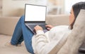 Mockup laptop. Woman looking at mock up blank white screen lying on sofa at home. woman using, working on laptop with blank screen Royalty Free Stock Photo