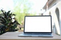 Mockup laptop computer with empty screen on wooden table at outdoor. Blank screen for your advertising text