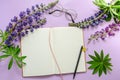 Mockup notebook with lupine flowers, eyeglasses and pen on a purple background. empty space for your text, top view
