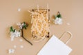 Mockup of an open gift box with peach colored paper shavings, white paper bag and apple flowers on a beige background. Flat lat, Royalty Free Stock Photo