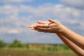 Mockup photo for unidentified child girl holding or giving something in her open palms against cloudy sky