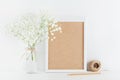 Mockup of picture frame decorated gypsophila flowers in vase on white working table with clean space for text and design your blog Royalty Free Stock Photo