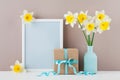 Mockup of picture frame decorated narcissus or daffodil flowers in vase and gift box for greeting on mother day. Royalty Free Stock Photo