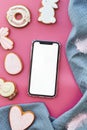 Mockup of screen phone among Easter seasonal aesthetics pastry cookies on pink background flat lay. Happy Easter