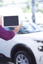 Mockup of seller`s tablet in car showroom with exclusive vehicle Royalty Free Stock Photo