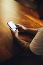 Mockup shot of man`s hand with tattoos holding cell phone with blank screen on desk at home office. Royalty Free Stock Photo