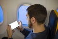 Mockup smartphone airplane. Young attractive european man holding blank screen smartphone in hands in airplane. Mock up for a game