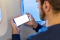 Mockup smartphone airplane. Young attractive european man holding blank screen smartphone in hands in airplane. Mock up for a game