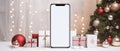 Mockup smartphone with blank screen on white table with christmas tree and gifts . Royalty Free Stock Photo