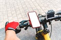 Mockup of a smartphone on the handlebars of a bicycle with an action camera, with the hand of a person with red gloves in the city