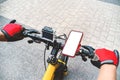 Mockup of a smartphone on the handlebars of a bicycle with an action camera, with the hand of a person with red gloves in the city