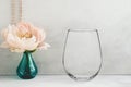 Mockup - stemless wine glass, next to a peony in a vase Royalty Free Stock Photo