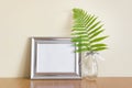 Mockup template with horizontal silver wide frame and glass vase with forest wild fern leaf