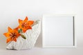Mockup template with square white wooden frame, porous white stone and orange lilies Royalty Free Stock Photo