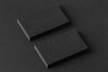 Mockup of two blank business cards stacks at black textured paper