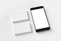 Mockup of two blank horizontal business cards and black cell-phone at white textured paper Royalty Free Stock Photo