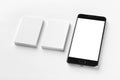 Mockup of two vertical business cards and black cell-phone with blank screen at white textured paper background. Royalty Free Stock Photo
