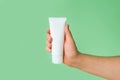 Mockup of unbranded white bottle tube for branding and label and male hand on a green background. Shaving foam or male skin care Royalty Free Stock Photo