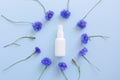 Mockup of unbranded white plastic spray bottle and floral frame of blue lowers on a pastel blue background. Natural organic spa Royalty Free Stock Photo