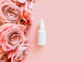 Mockup of unbranded white plastic spray bottle and pink roses on a pastel pink background. Bottle for branding and label.