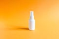 Mockup of unbranded white plastic spray bottle on a textured bright orange background. Natural organic spa cosmetics