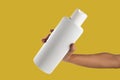 Mockup of unbranded white shampoo or conditioner bottle on yellow background