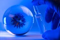 Mockup of virus in a glass sphere and a hand in medical glove holds an ampule with covid-19 vaccine or medicine.