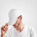 Mockup of a white baseball cap on a guy, straightening visor, side view, textile hat for presentation of design, pattern