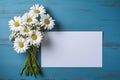 mockup white blank paper sheet with bouquet white daisies flowers top view on blue wooden background, floral template empty card Royalty Free Stock Photo