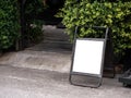 Mockup white blank vertical rectangle space of standing signage outdoor, A shape, with old black iron frame. Royalty Free Stock Photo