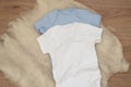 Mockup of white and blue baby bodysuit on wood background. Blank baby clothes template mock up. Flat lay styled stock photo