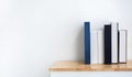 Mockup of white and blue blank book spines on wooden shelf on white background.