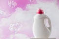 Mockup of a white bottle with gel for washing clothes against the background of pink clouds and flying soap bubbles.