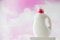 Mockup of a white bottle with gel for washing clothes against the background of pink clouds.