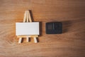 Mockup of a white business card on an easel with an action camera, on a wooden table background.